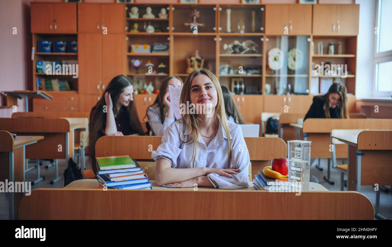 Schoolgirl poses with textbooks at her desk in her class Stock Photo ...