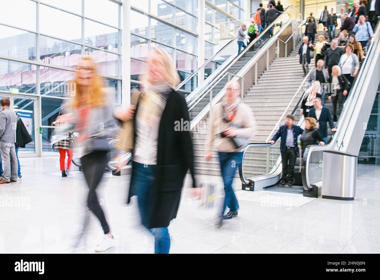 Business people on escalator at business trade fair Stock Photo