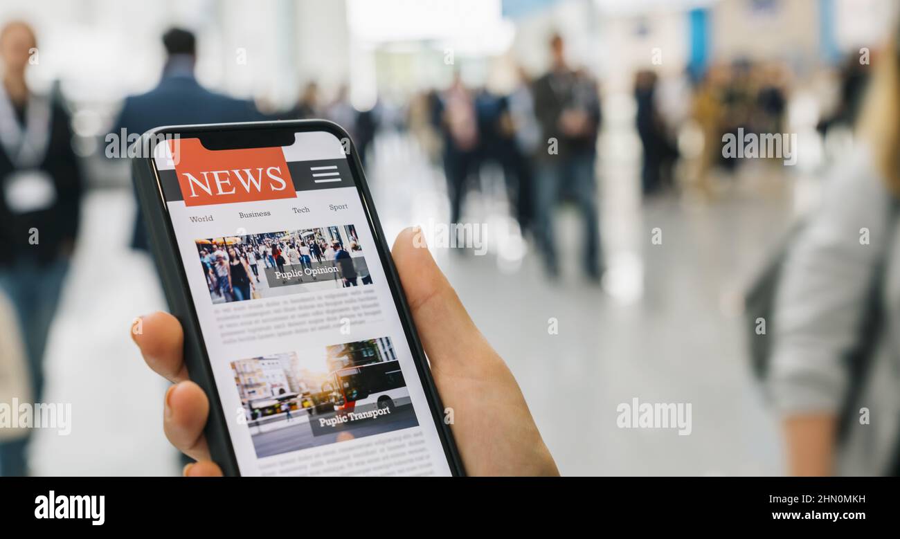 Online news on a mobile smartphone. Close up of businesswoman reading news or articles in a smartphone screen application. Hand holding smart device. Stock Photo