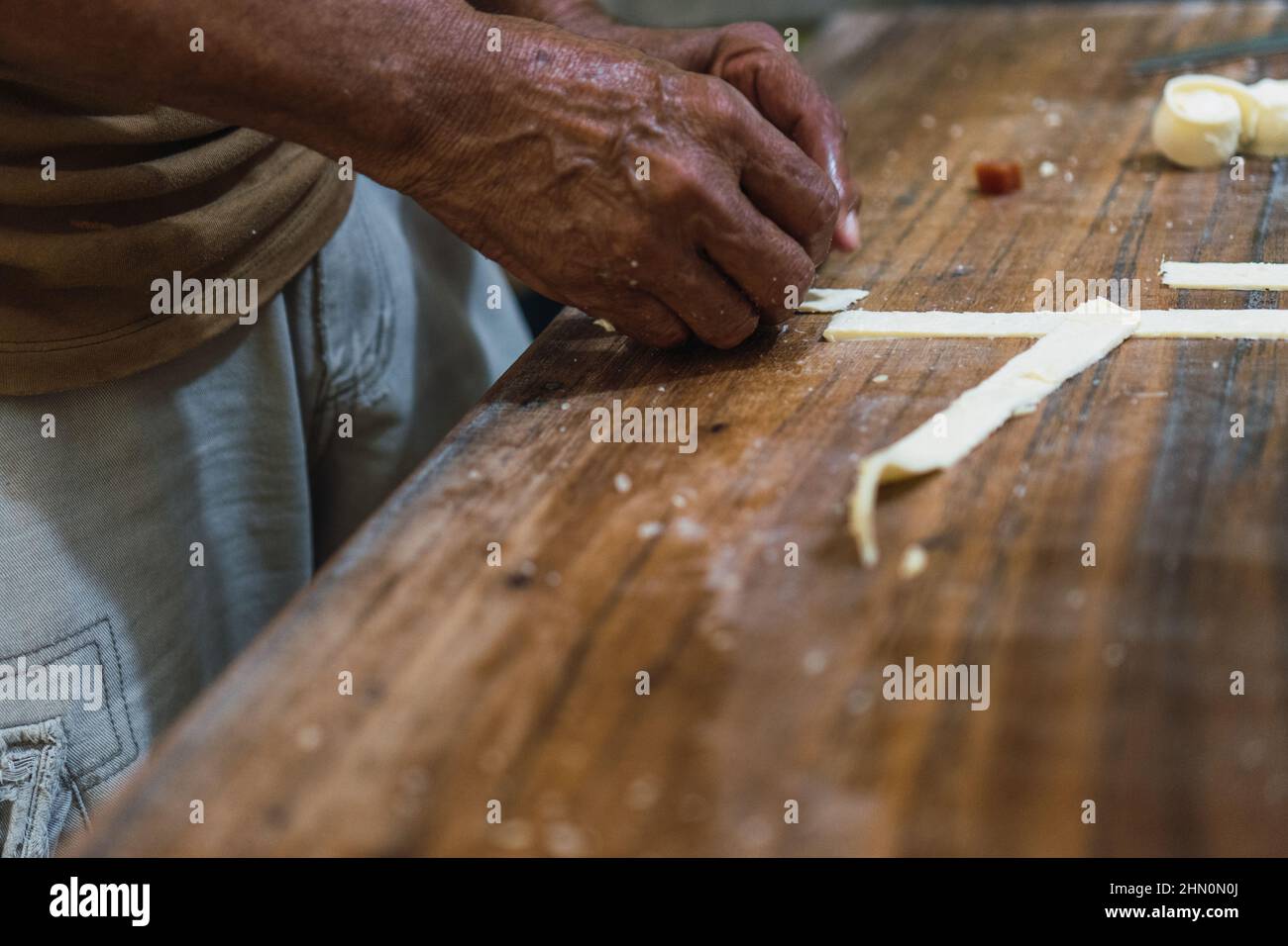 Man's hands cutting cheese on a wooden table Stock Photo