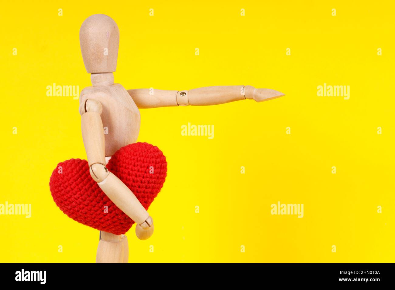 wooden man with a red heart in his hands on a yellow background. High ...
