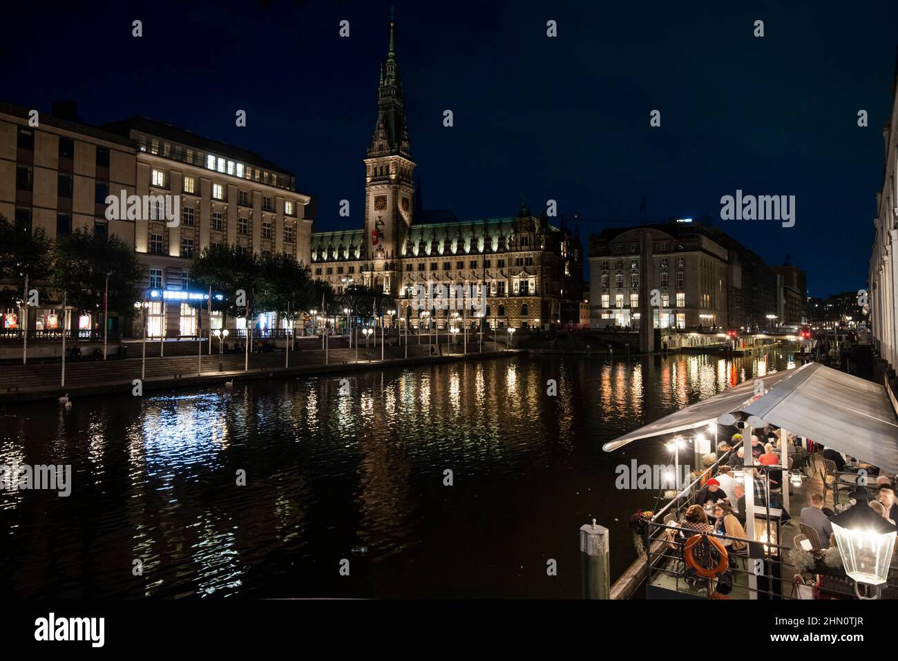 September 27 2018: Night view of the Hamburg city hall from the bridge in Alster Arkaden and one of its terraces on the banks of the Alster river Stock Photo