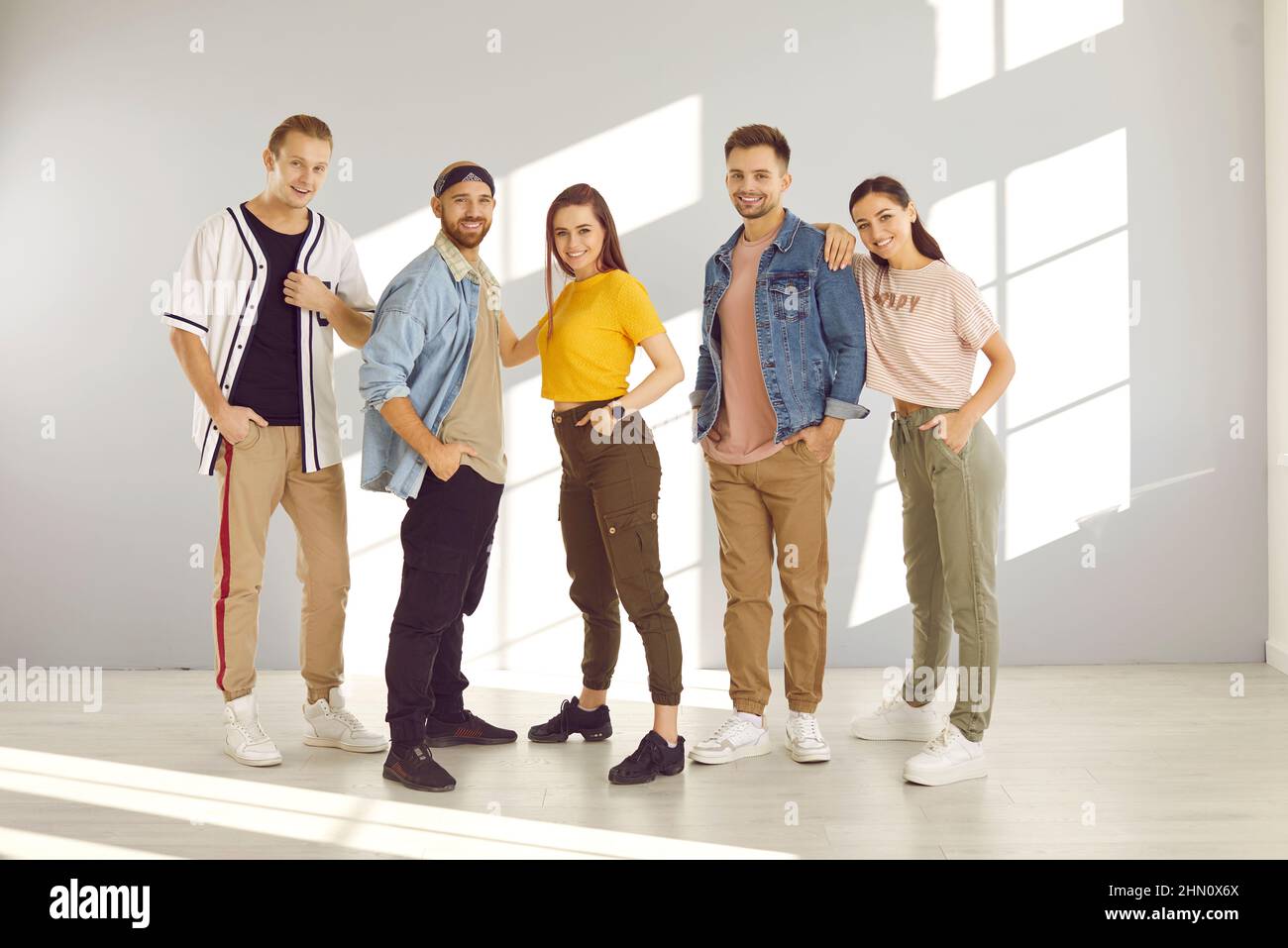 Group of happy confident young people wearing modern casual clothes posing in studio Stock Photo