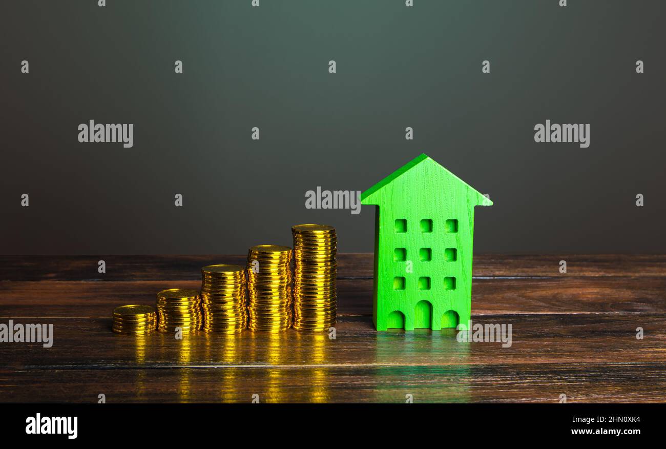 Growing stacks of coins and a green house. Investment in green