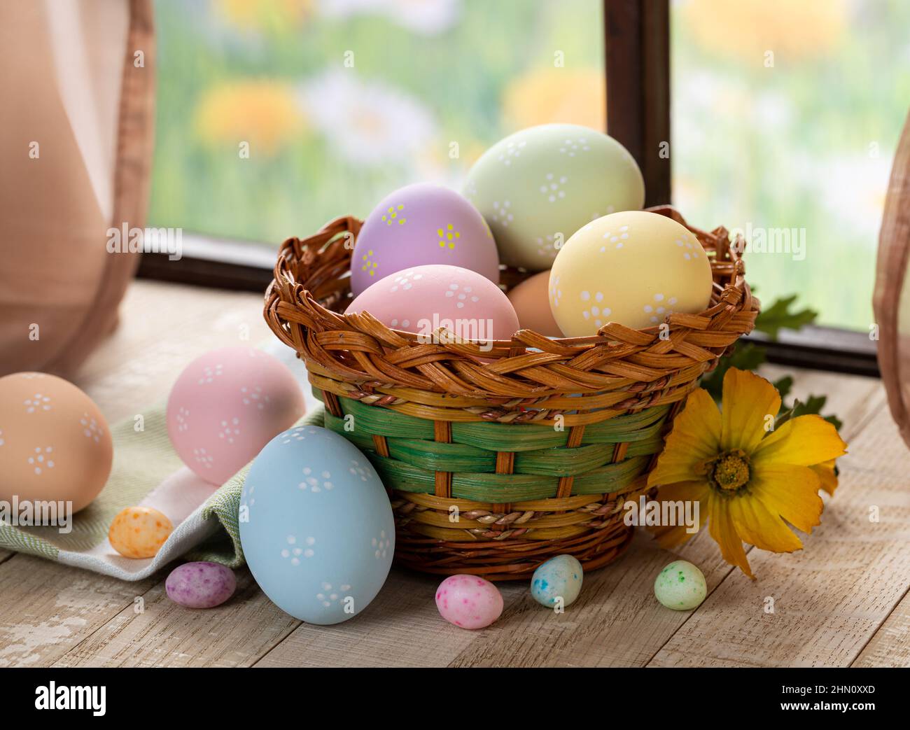 Colorful easter eggs in a basket and on a rustic wooden table by a ...