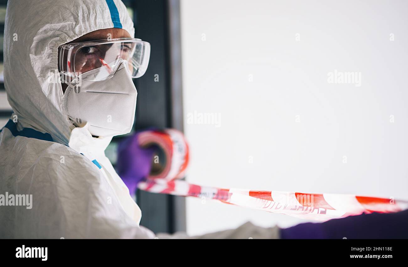 Doctor seals off contaminated area with barrier tape during coronavirus (Coivd-19) epidemic in a clinic at the  intensive care unit Stock Photo
