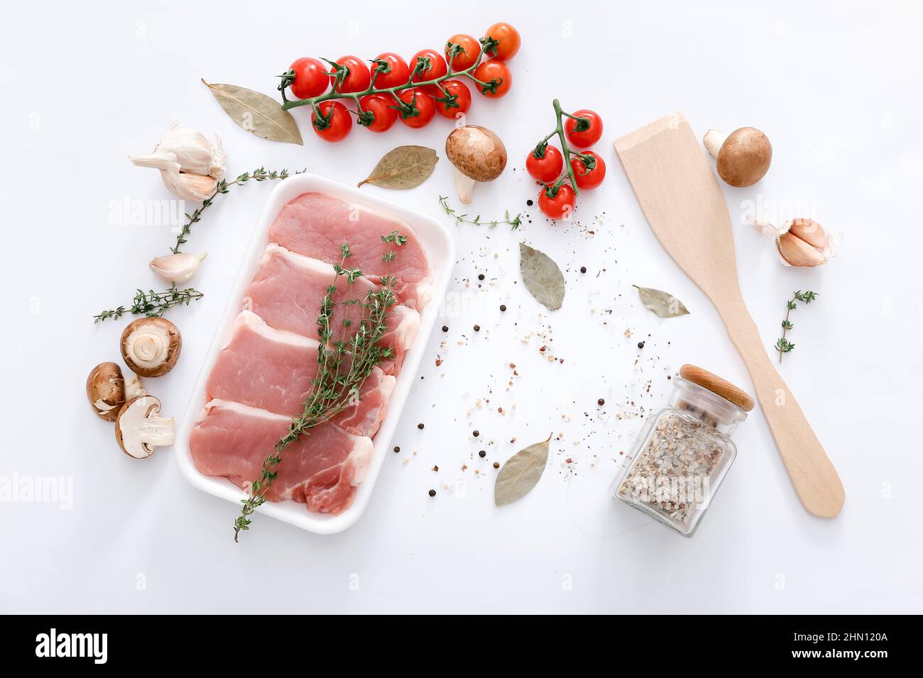 Raw meat and wooden spatula with different spices and vegetables on grey table background, top view Stock Photo