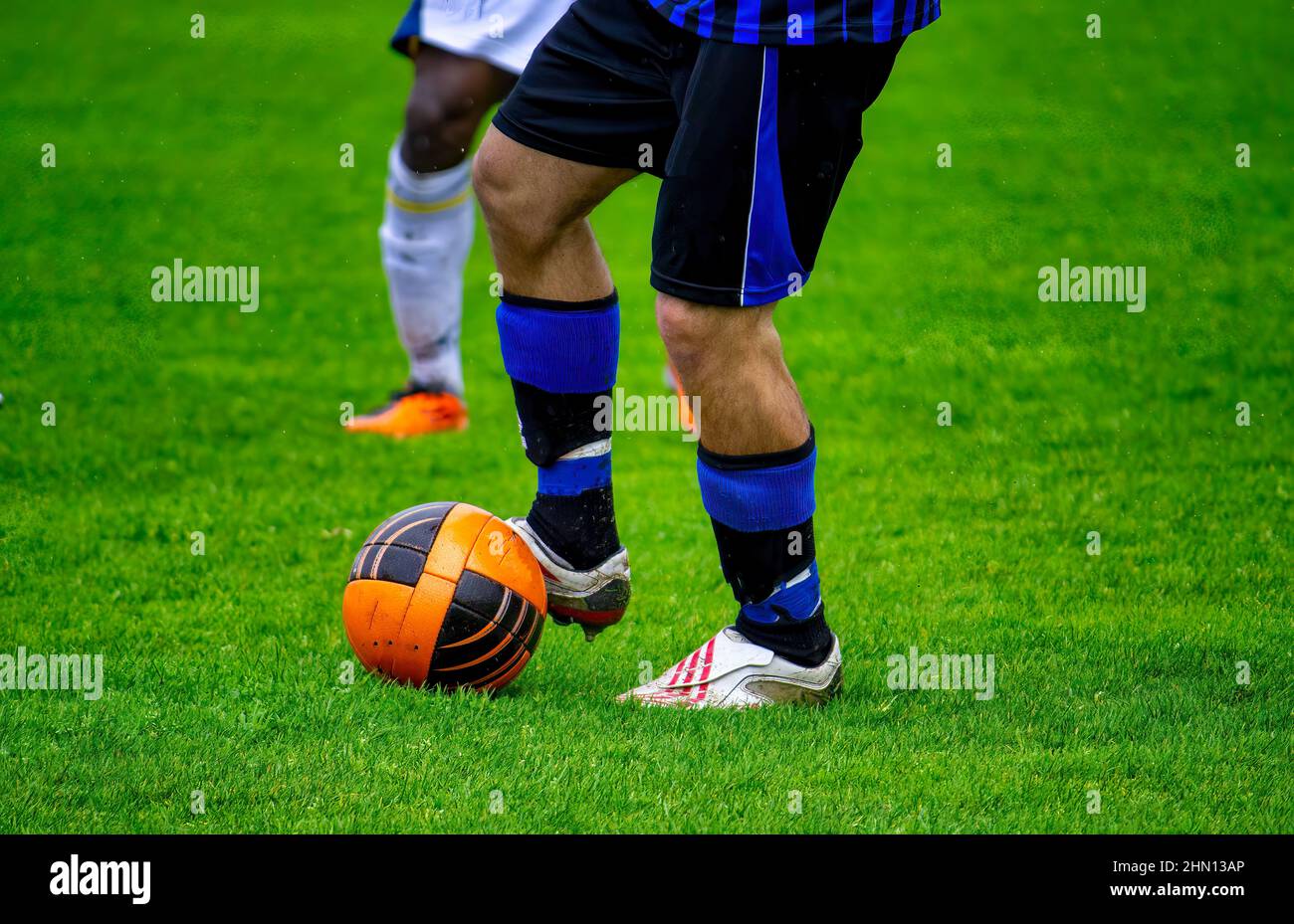 Football players tackling for the ball on soccer pitch Stock Photo