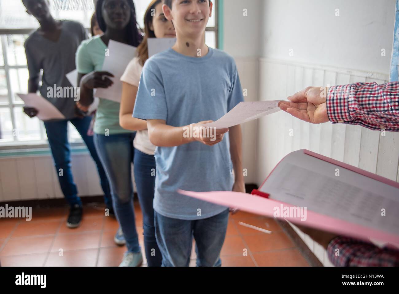 Group of multi ethnic high school students handing in class assignments