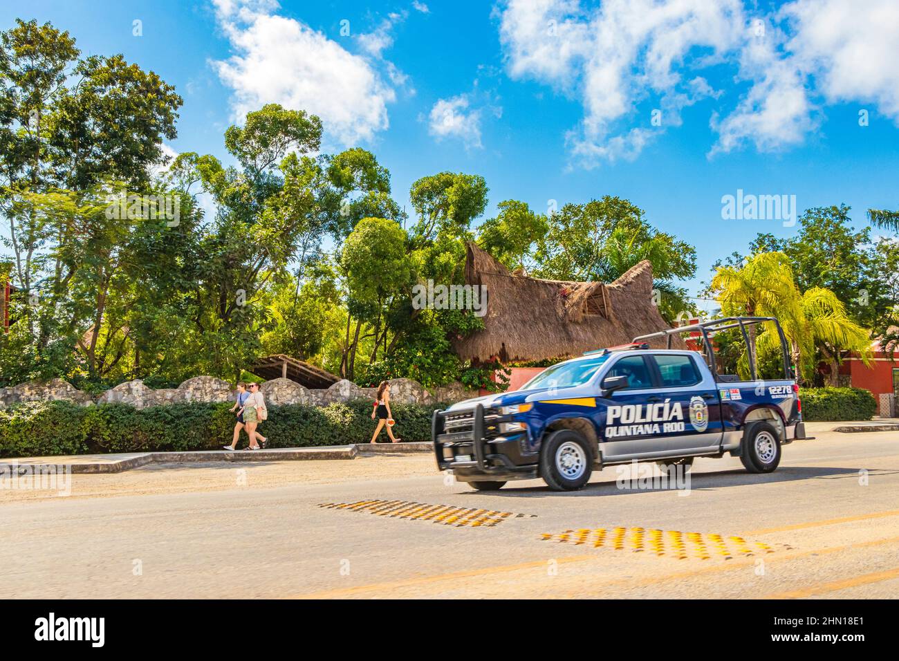 Tulum Mexico 02. February 2022 Police car pickup truck is driving fast thru typical colorful street road and cityscape with cars traffic palm trees ba Stock Photo