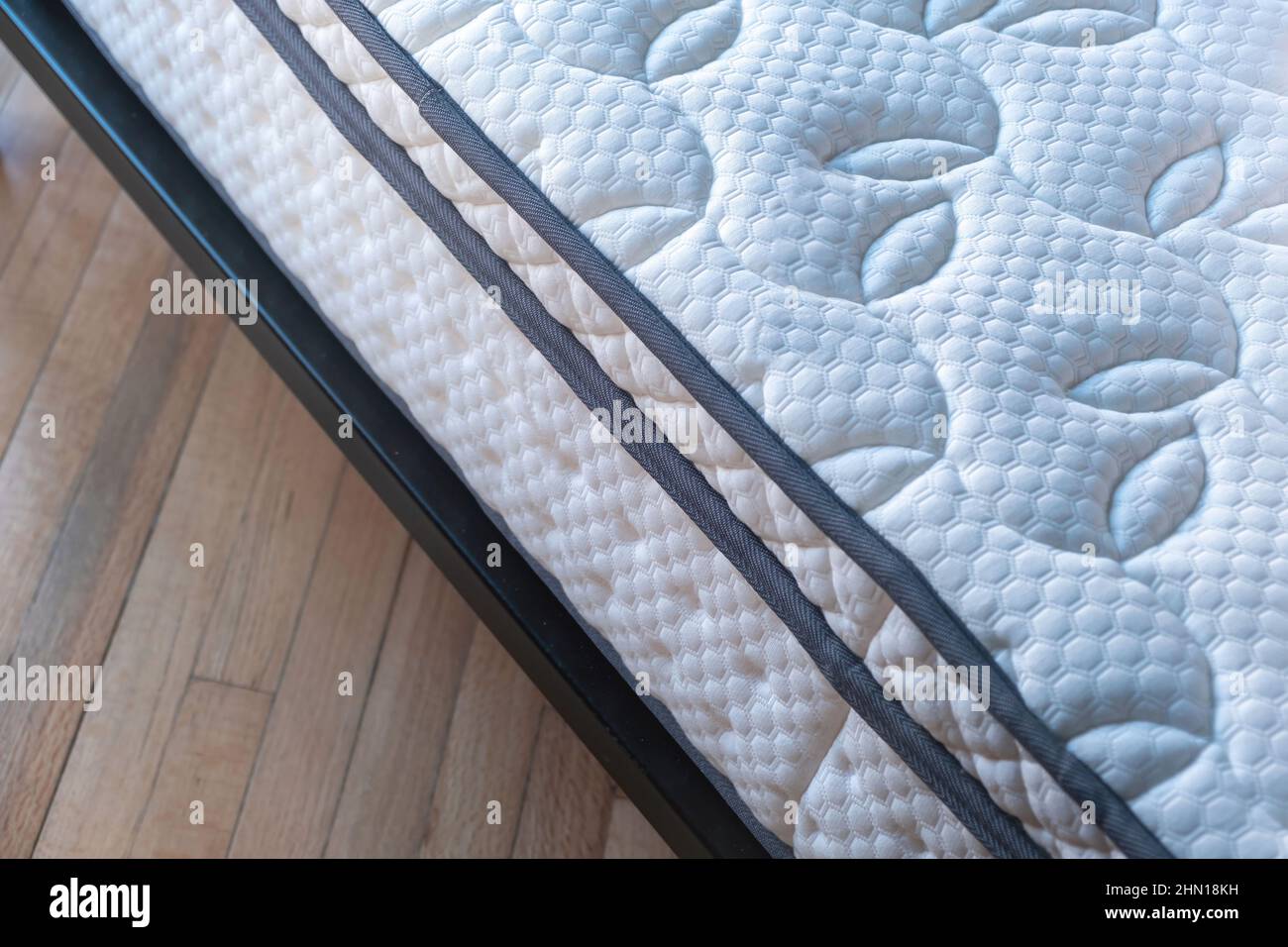 Mattress new and clean on a bed close up. Home bedroom interior detail, high angle view, wooden floor background. Comfort and healthy sleep and relaxa Stock Photo