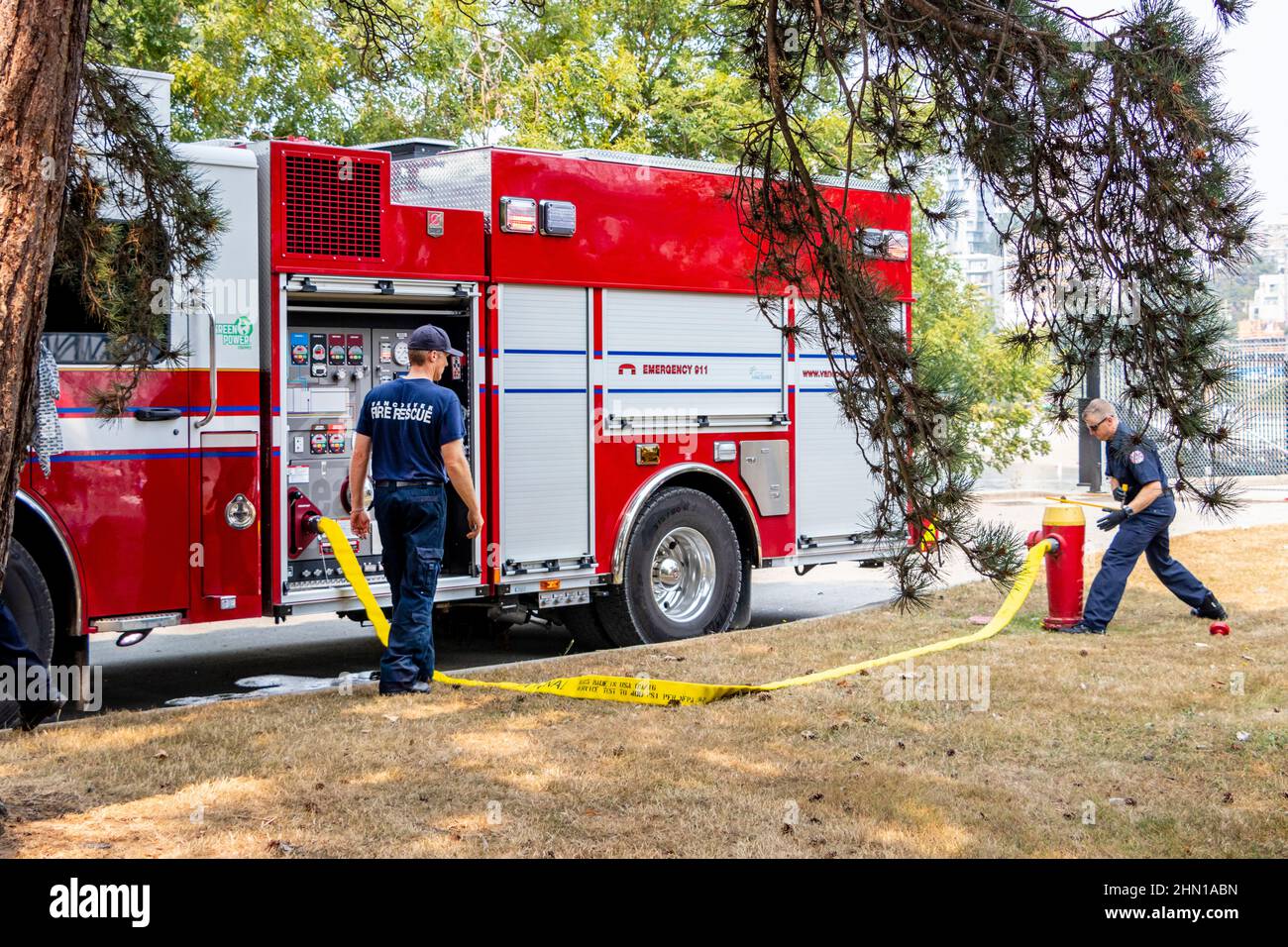 fire crew connect fire engine appliance to a hydrant with hose in Vancouver BC canada Stock Photo