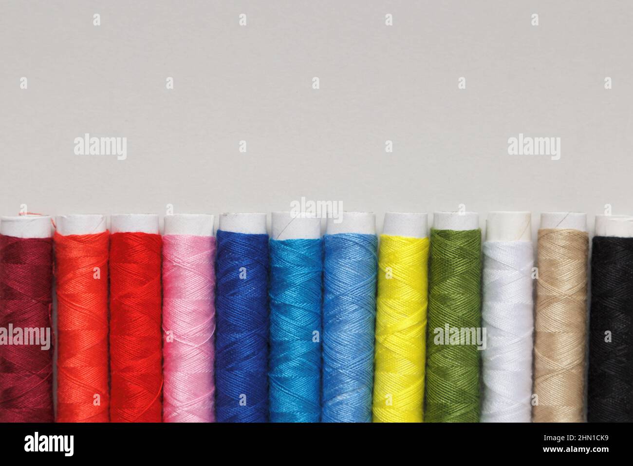 Multicolored threads in a row on a gray background with copy space. Stock Photo