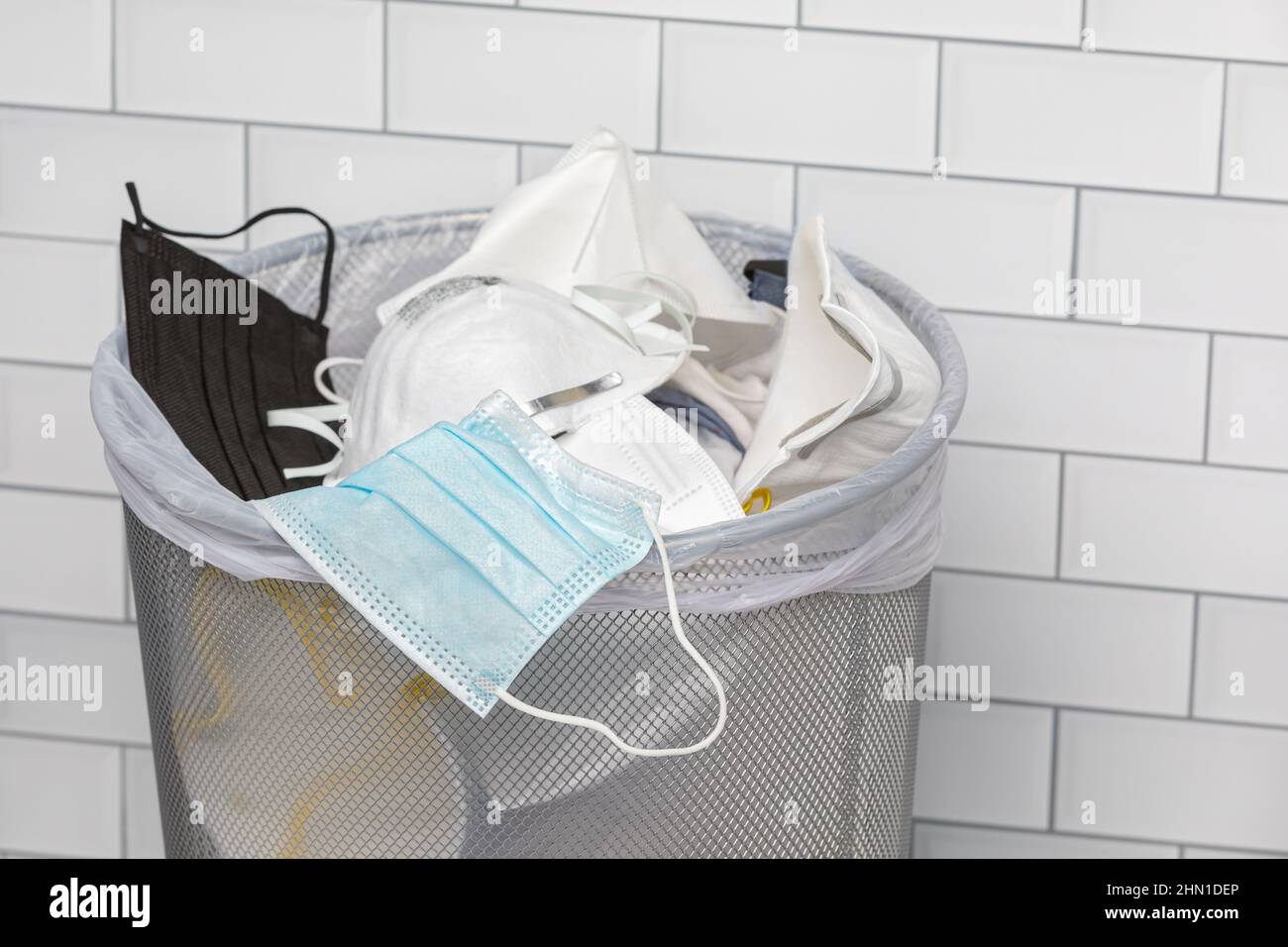 Face masks in garbage can. Covid-19 face covering mandate, disposal and requirement. Stock Photo