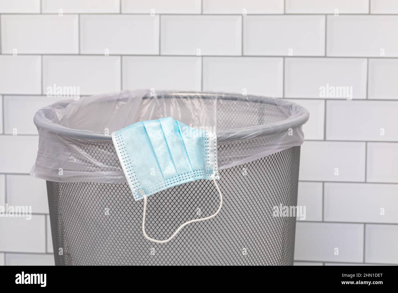 Blue surgical face mask in garbage can. Covid-19 face covering mandate, disposal and requirement. Stock Photo