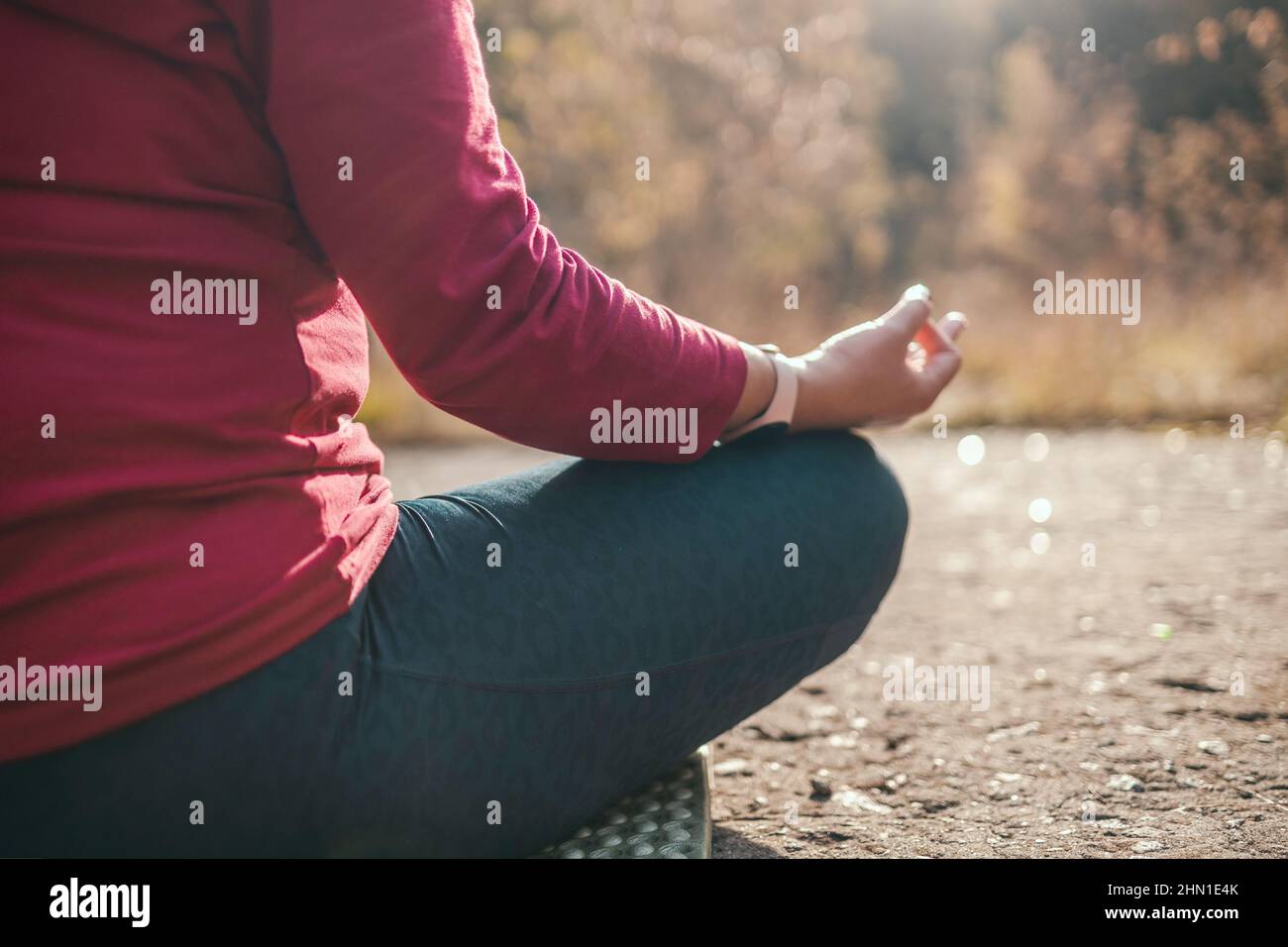 Sport fitness woman sitting in yoga lotus pose outdoor at sunrise, meditation for balance, enjoying nature Stock Photo