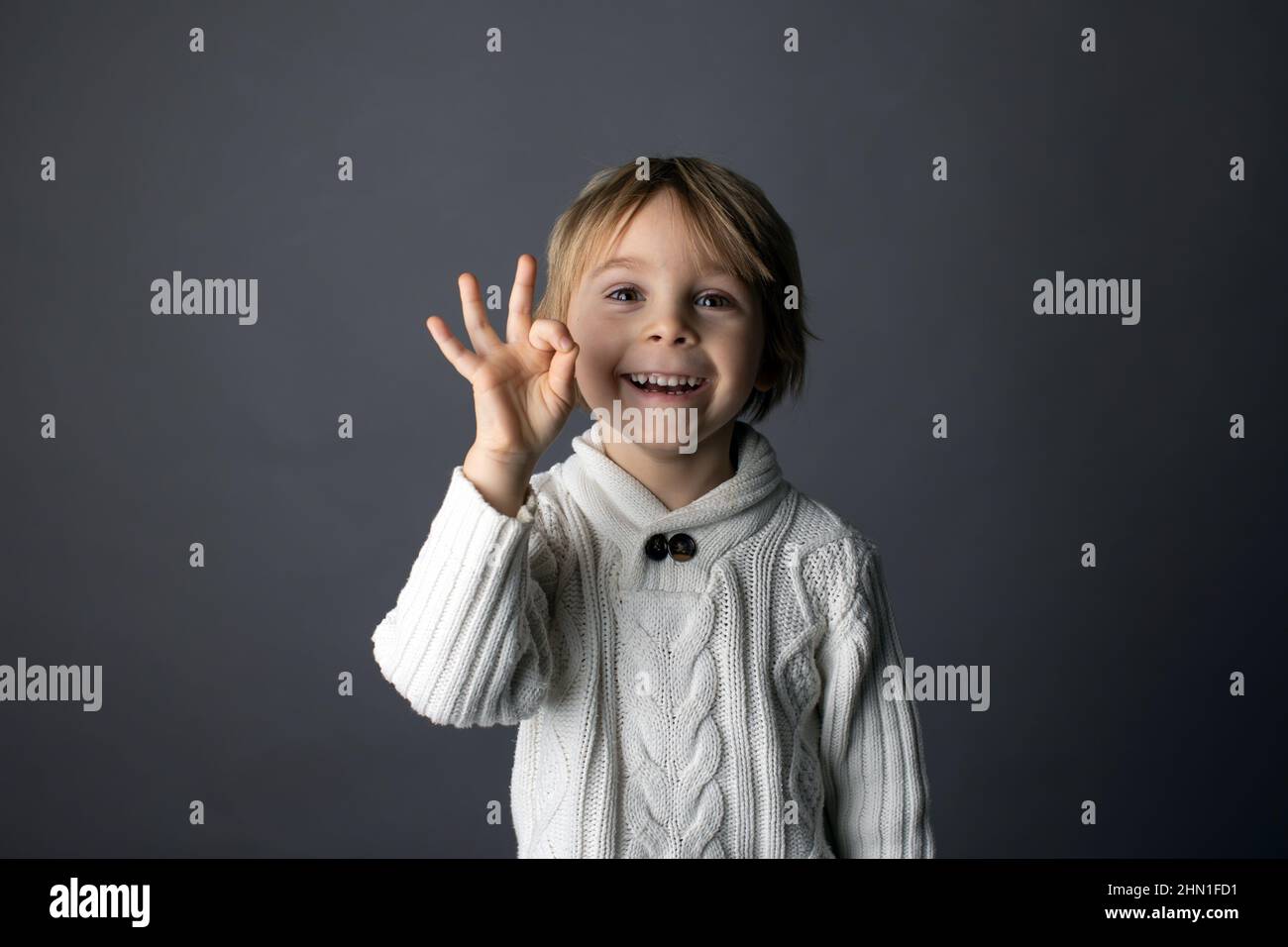 Cute little toddler boy, showing OK gesture in sign language on gray ...