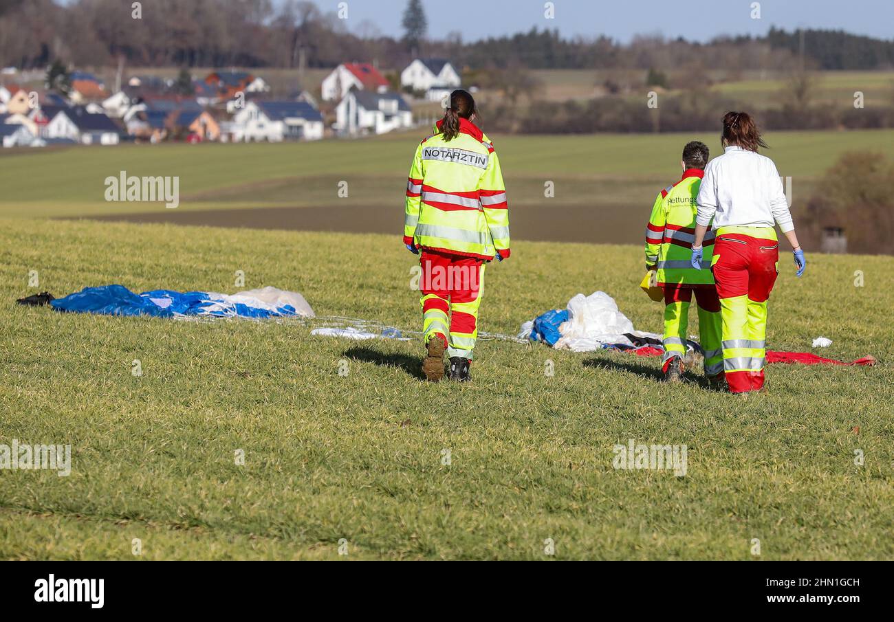 Bad Saulgau, Germany. 13th Feb, 2022. Emergency paramedics and an emergency doctor walk across a field after treating a seriously injured parachutist. In the background, the parachute of the casualty. Credit: Thomas Warnack/dpa/Alamy Live News Stock Photo