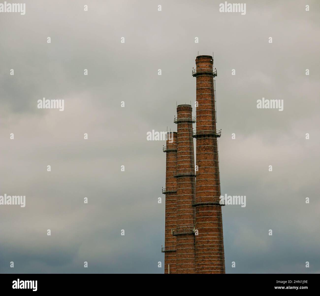 Air pollution from smoke coming out of three factory chimneys. The concept of air pollution, environmental problems, atmospheric emissions Stock Photo