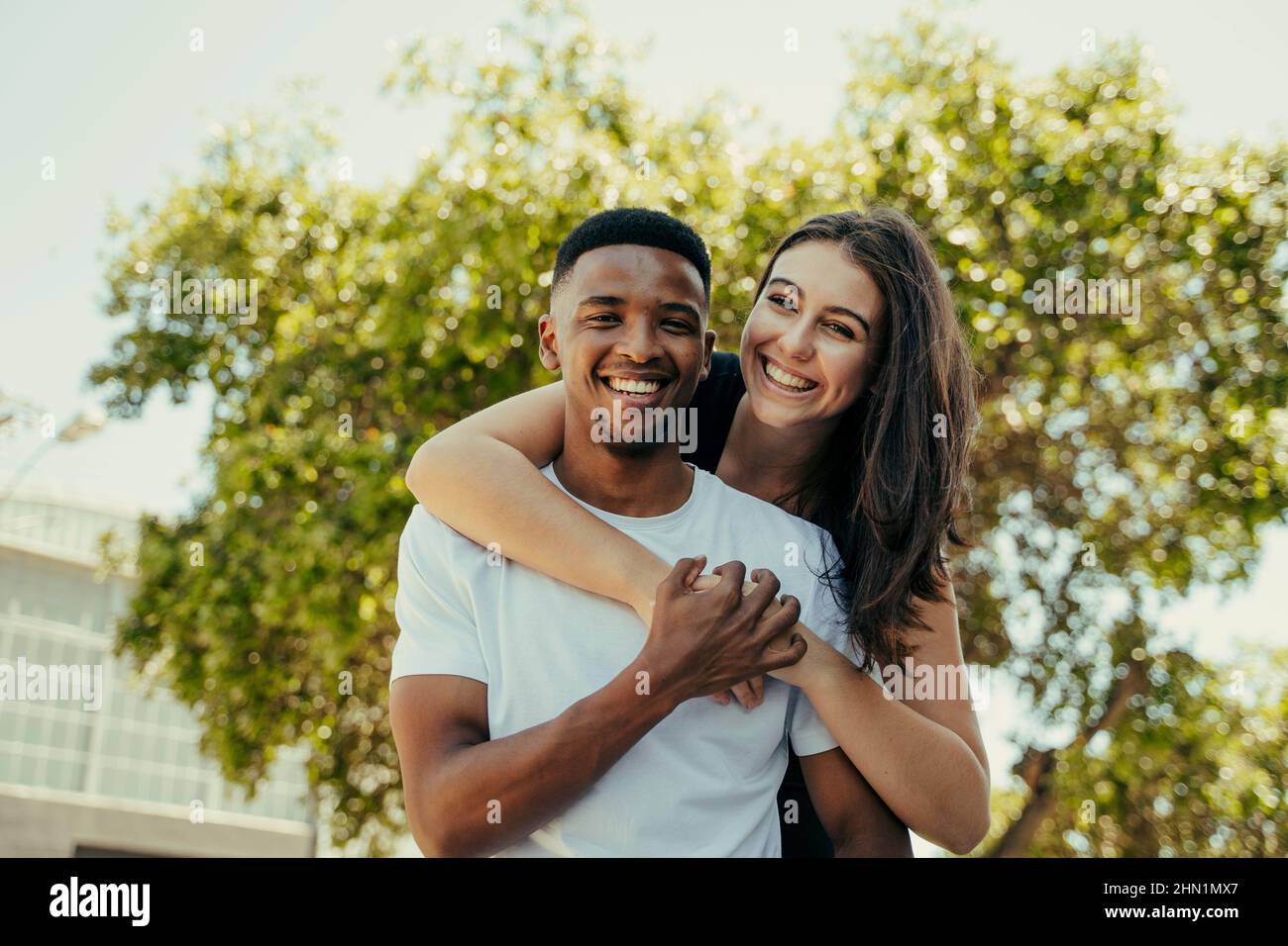 Portrait of biracial couple hugging in the park Stock Photo - Alamy