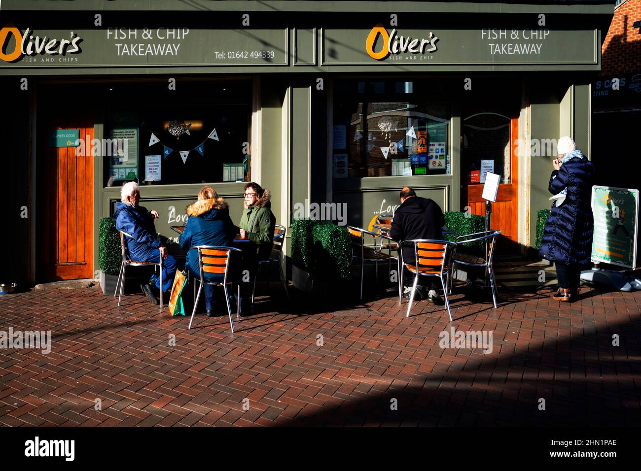 Oliver's Fish and Chip shop Takeaway in Redcar Cleveland North Yorkshire England UK with elderly customers eating outside in fine winter sunshine Stock Photo
