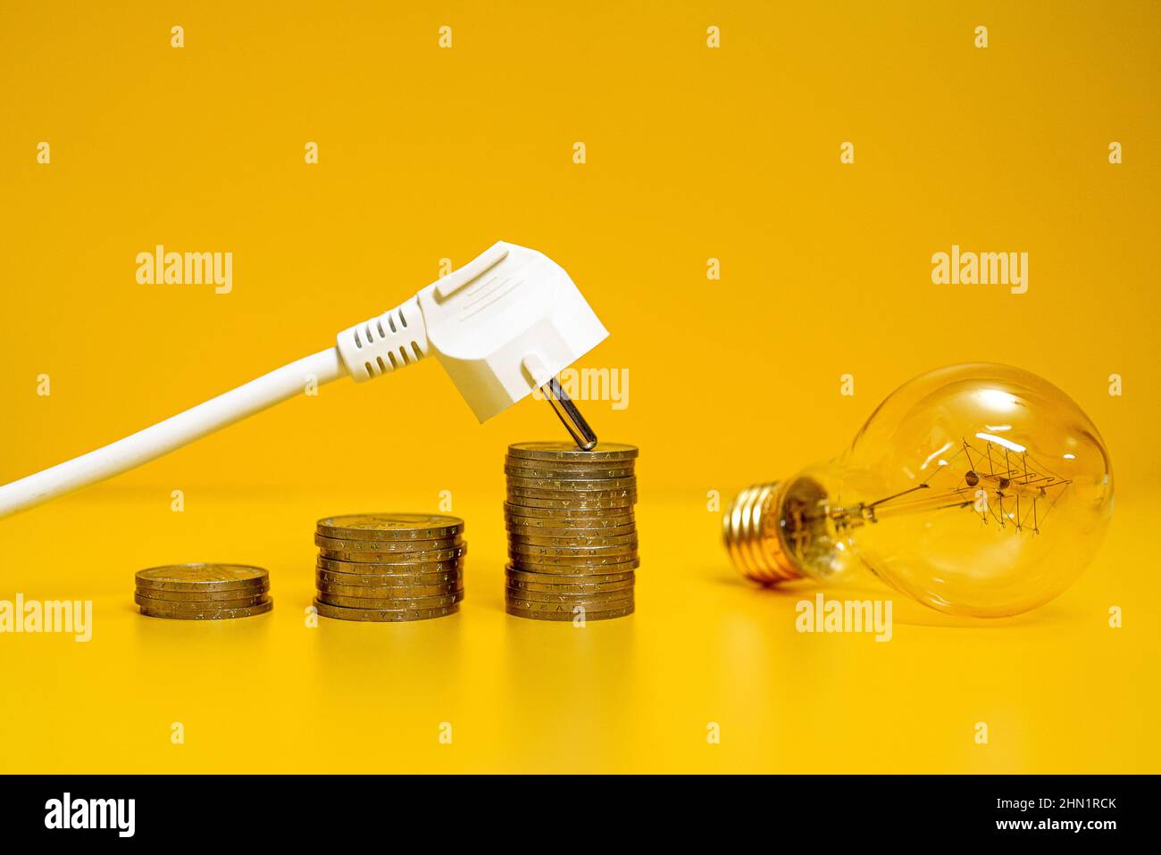 Concept of rising electricity prices. AC power plug, coins and lamp ...