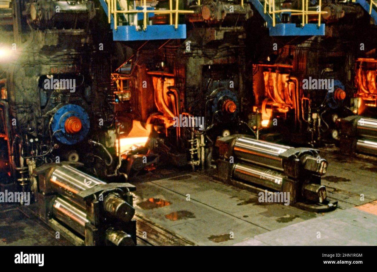 A mid-1980s view inside the Port Talbot Steelworks, an integrated steel production plant in Port Talbot, West Glamorgan, Wales, UK. Inside the mill hot sheet-steel is being rolled out on the production line. This image is from a vintage colour transparency – a vintage 1980s photograph. Stock Photo