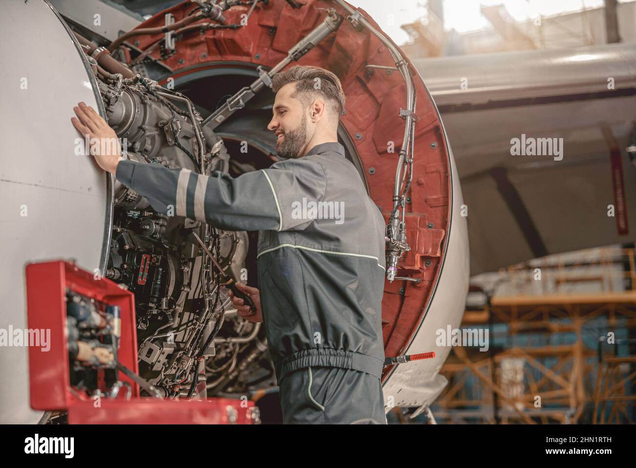 Joyful male mechanic repairing airplane in hangar Stock Photo - Alamy