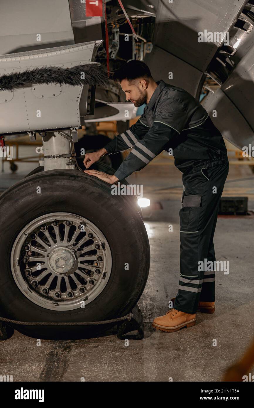 Male mechanic repairing airplane wheel in hangar Stock Photo