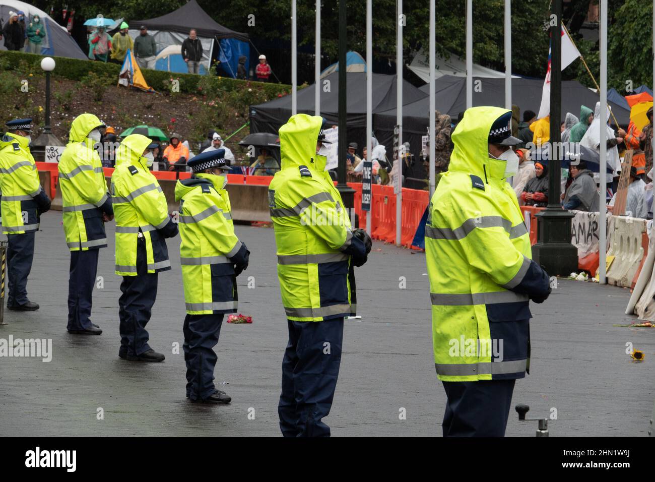 Masked police keep watch at covid vaccine mandate protest outside parliament in Wellington, New Zealand, February 13, 2022 Stock Photo