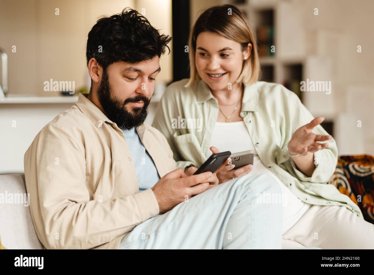 White couple using cellphones while sitting on couch at home Stock Photo