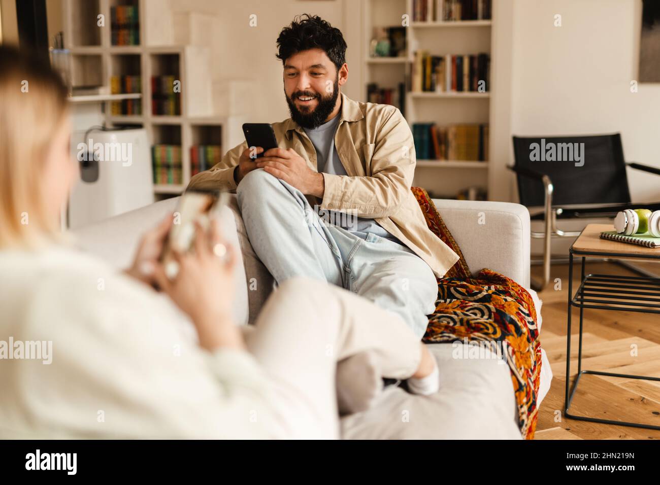 White couple using cellphones while sitting on couch at home Stock Photo