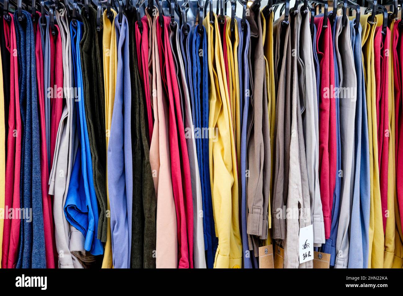 Rail of men's trousers for sale on market stall, east London, UK. Stock Photo