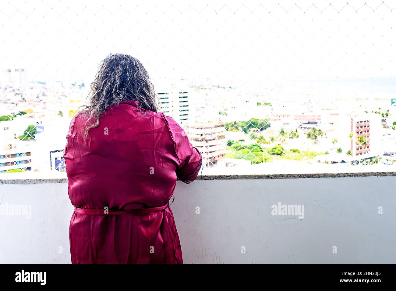 a woman from the back in a purple dress looking at the horizon. Salvador, Bahia, Brazil. Stock Photo