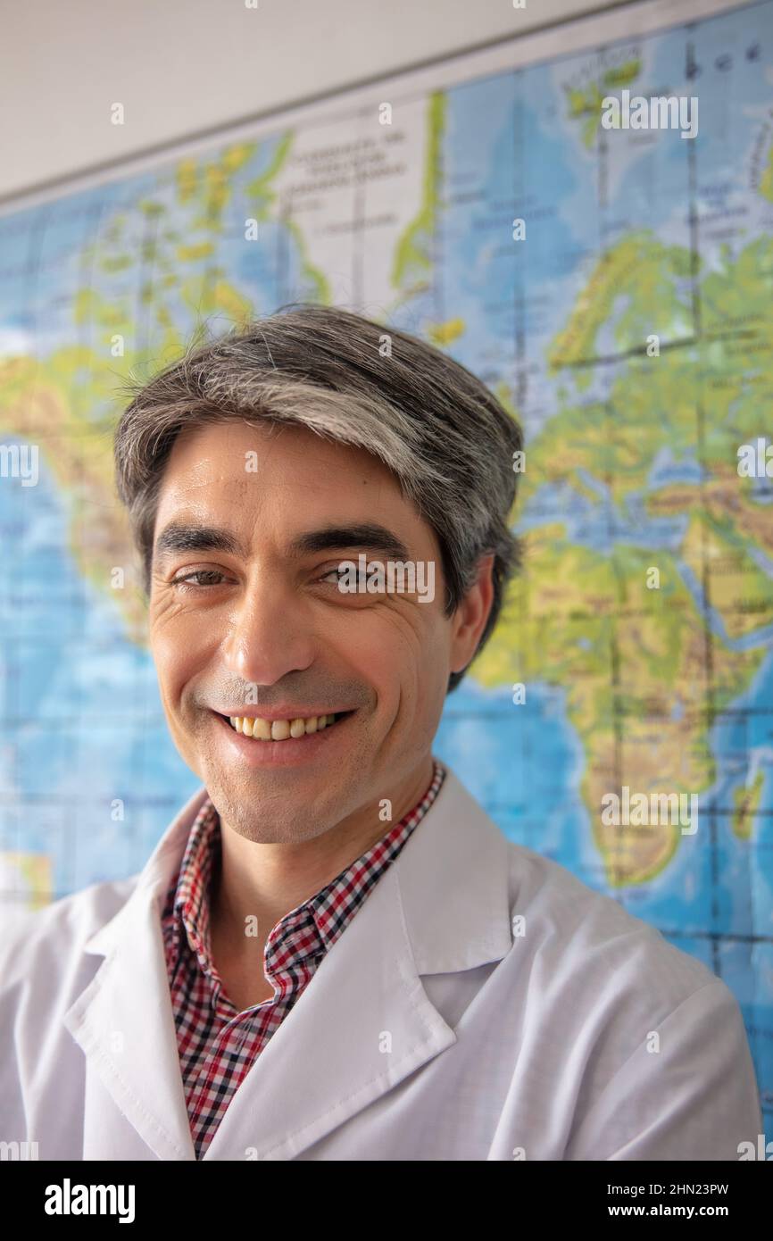 Happy confident teacher smiling to the camera with a geographical map on the background Stock Photo
