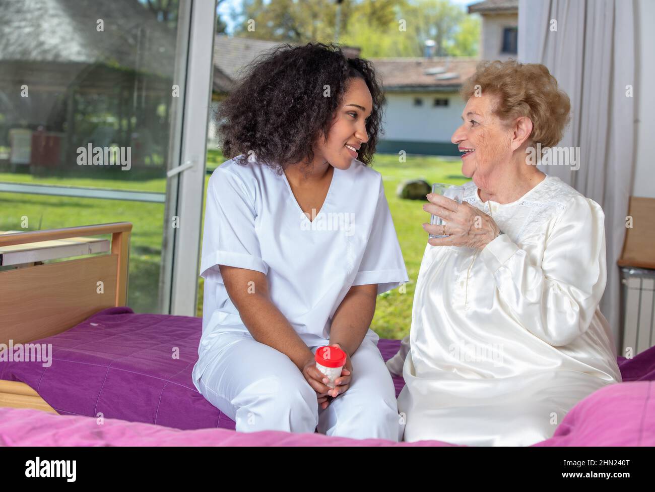 Caucasian female senior smiling with nurse at rehab clinic. Retired elderly people living their life at its best Stock Photo