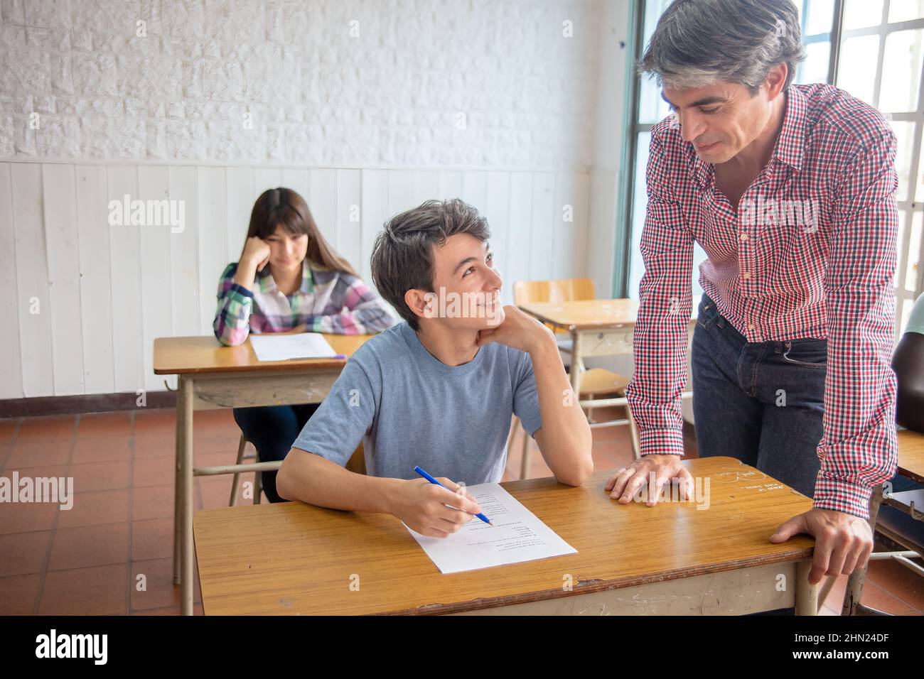 Group of multi ethnic high school students having test at classroom, teacher supervising Stock Photo