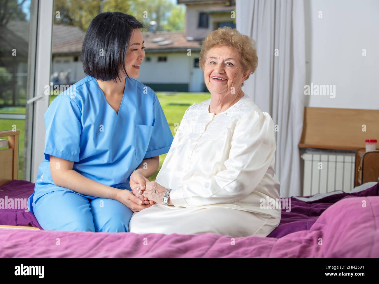 Caucasian female senior smiling with nurse at rehab clinic. Retired elderly people living their life at its best Stock Photo
