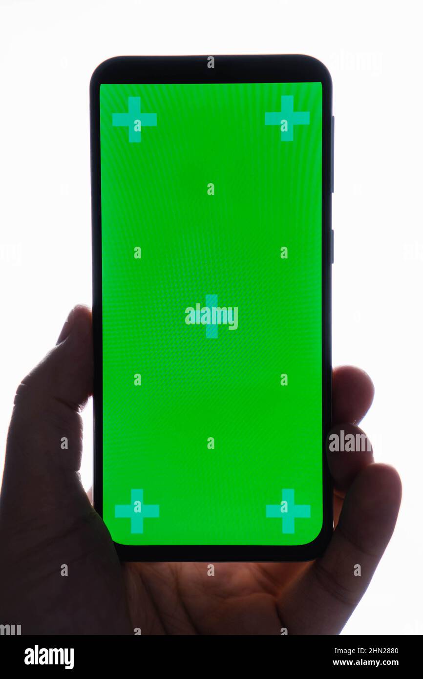 Close up of hand holding modern smartphone with green touch screen ...