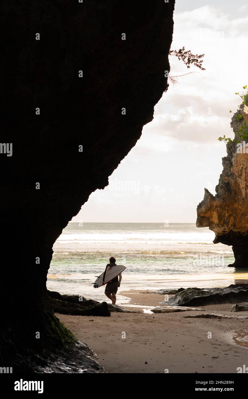 A man walking on the beach with a surfboard Stock Photo - Alamy