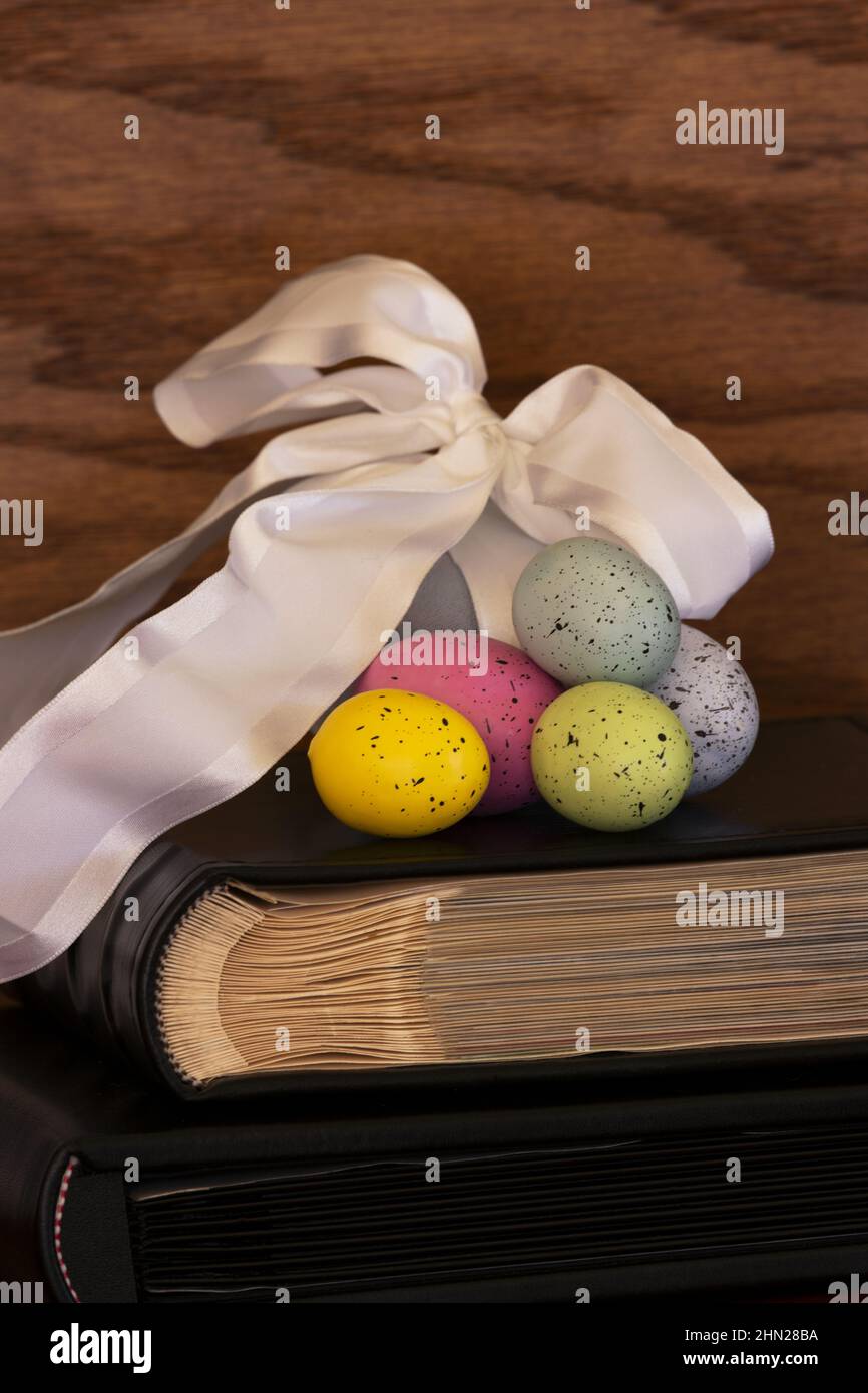 Making Easter memories grow with cherished traditions like colored Easter eggs; giving gifts; and filling photo albumsin vertical format on wood backg Stock Photo