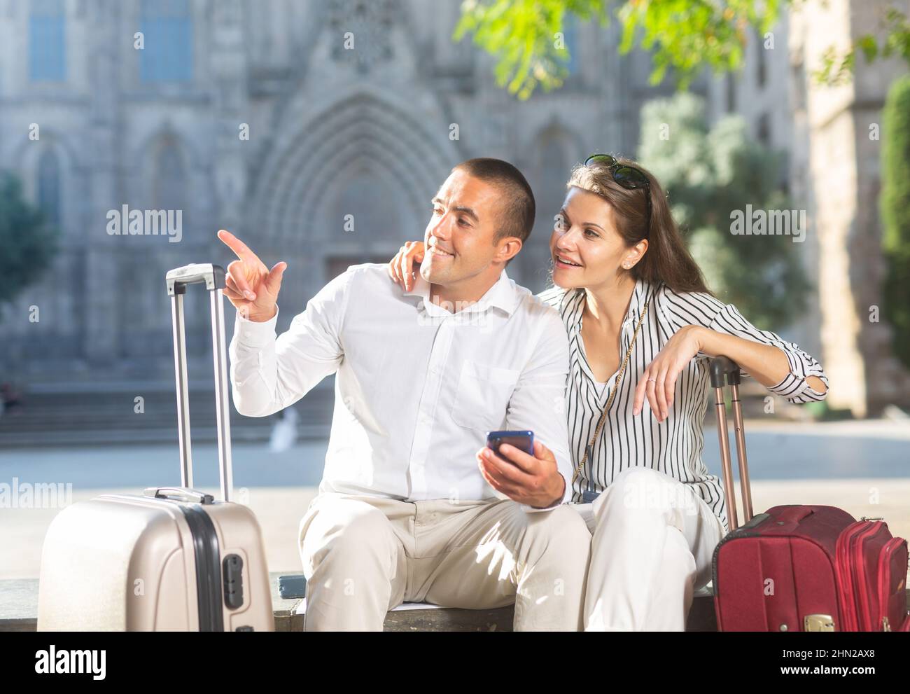 Couple of travelers resting on bench, looking at sights Stock Photo - Alamy