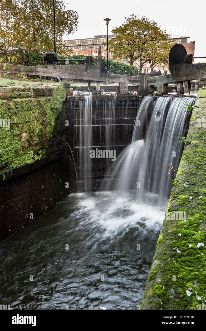 Lock on the Rochdale canal with water overflowing and leaking through the gates, Manchester, England, UK Stock Photo