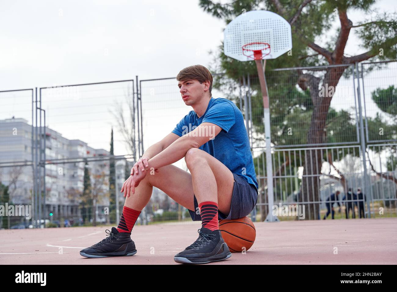 basketball player sitting on the ball on the court Stock Photo