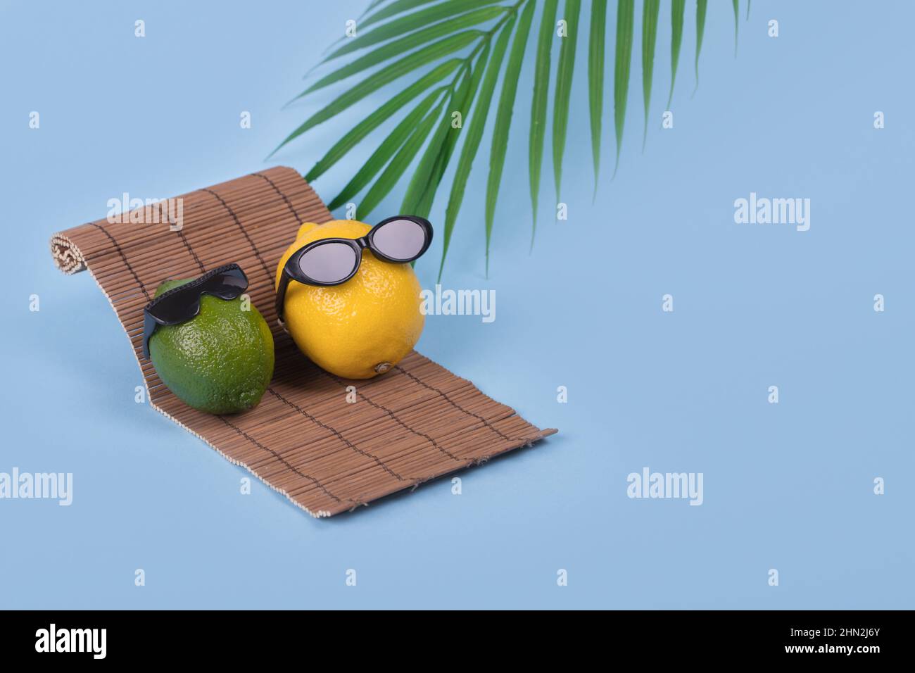 Creative fun idea with a lemon and lime in sunglasses lying on a sun bed on a bright blue background. Minimal travel and vacation concept, summer styl Stock Photo