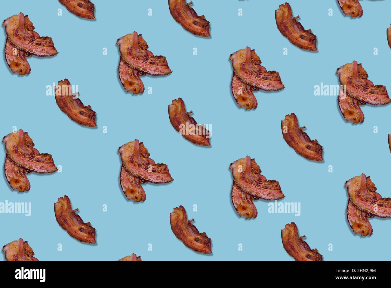 Pattern made lot of crispy bacon slices on bright blue background. Minimal and creative breakfast concept. Top view. Flat lay. Stock Photo