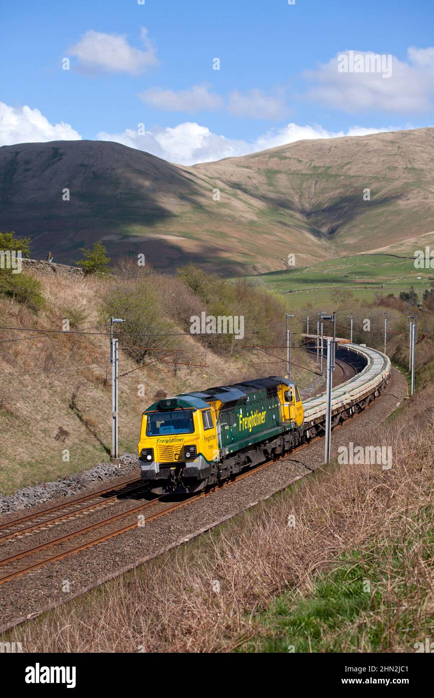 Freightliner class 70 diesel locomotive in the Cumbrian countryside on the west coast mainline with freight train carrying materials for Network Rail Stock Photo