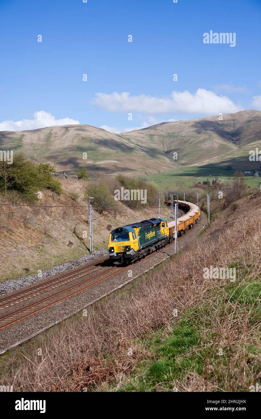 Freightliner class 70 diesel locomotive in the Cumbrian countryside on the west coast mainline with freight train carrying materials for Network Rail Stock Photo