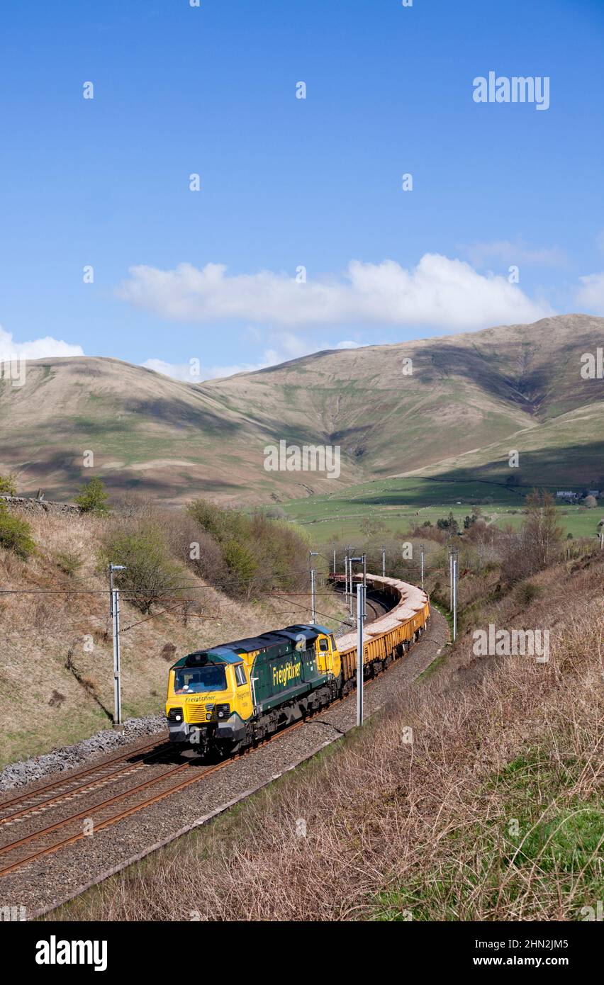 Freightliner class 70 diesel locomotive in the Cumbrian countryside on the west coast mainline with freight train carrying materials for Network Rail Stock Photo