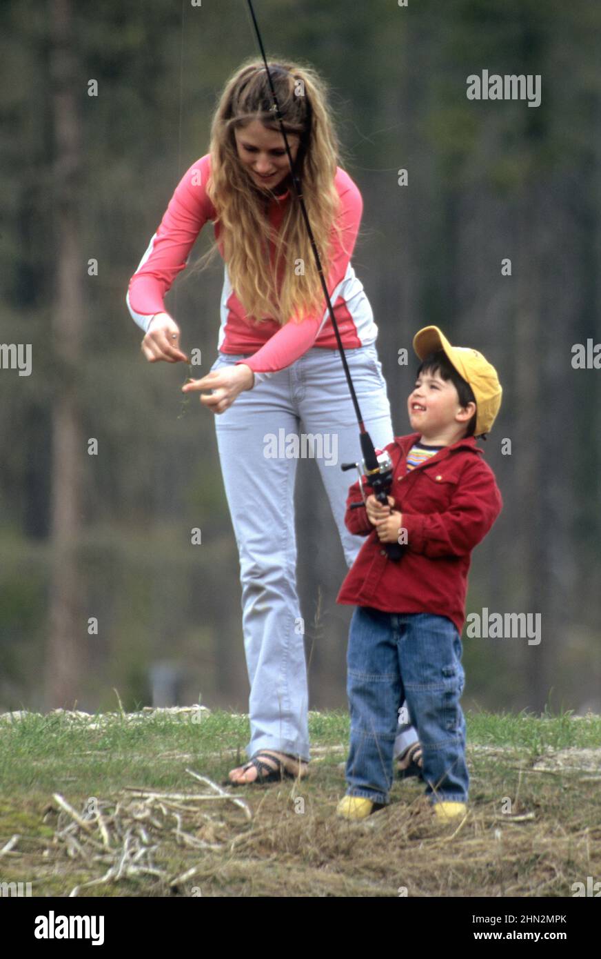 Mother baiting a fishing hook for her young son near West Glacier, MT Stock Photo